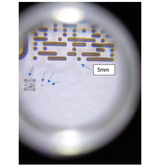 In the picture there are five QR codes in glass surface. The biggest that is only partly shown in the picture is 5 mm, the biggest code fully shown is 0,5 mm, then 0,05 mm, 0,02mm and the last one hardly seen in the picture is 0,01mm 